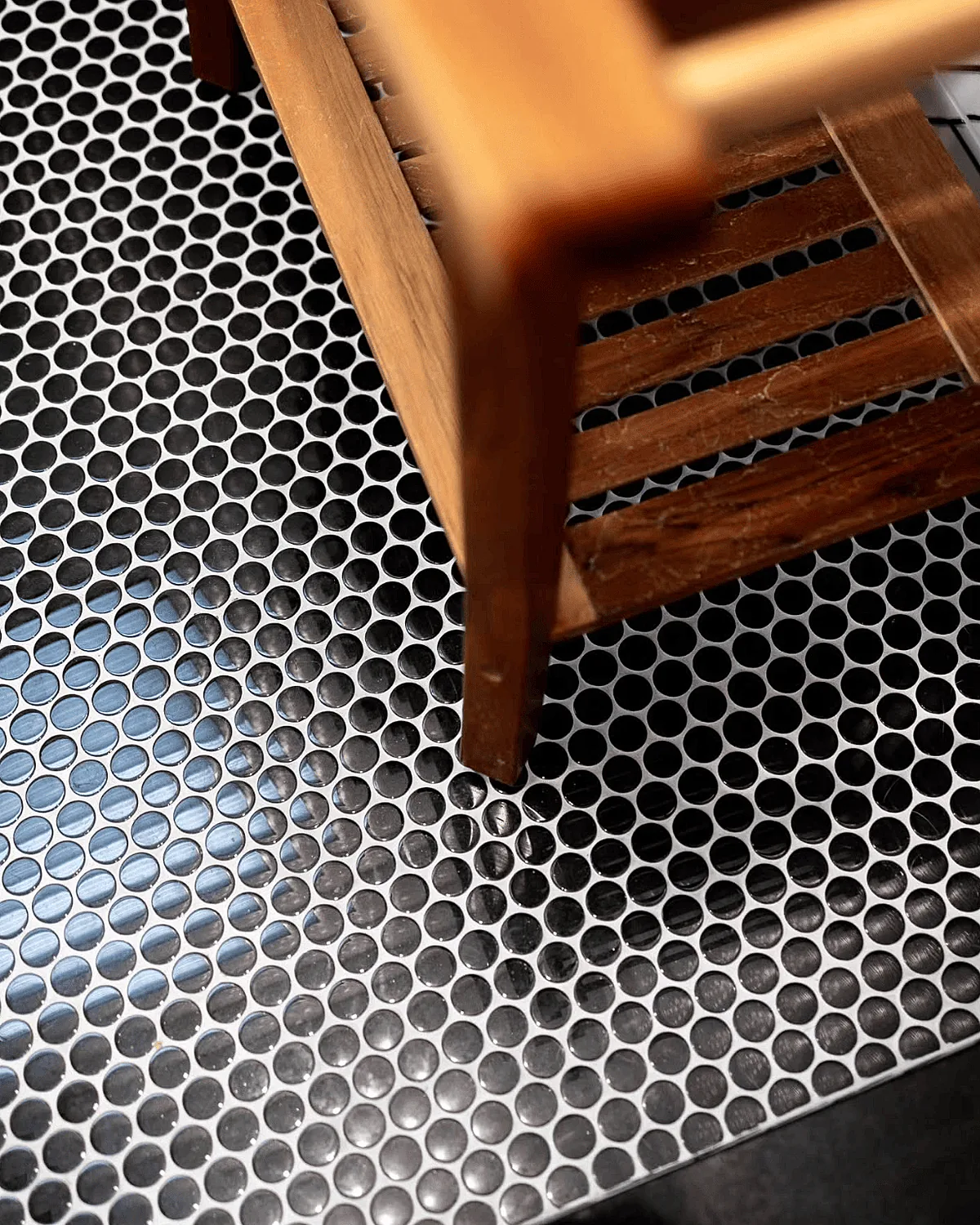Black and white penny round floor tile with a teak bench
