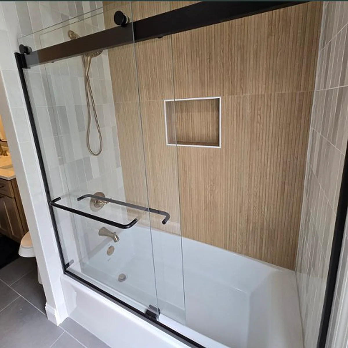 Tub and shower combo with a sliding glass door and wood-look tile
