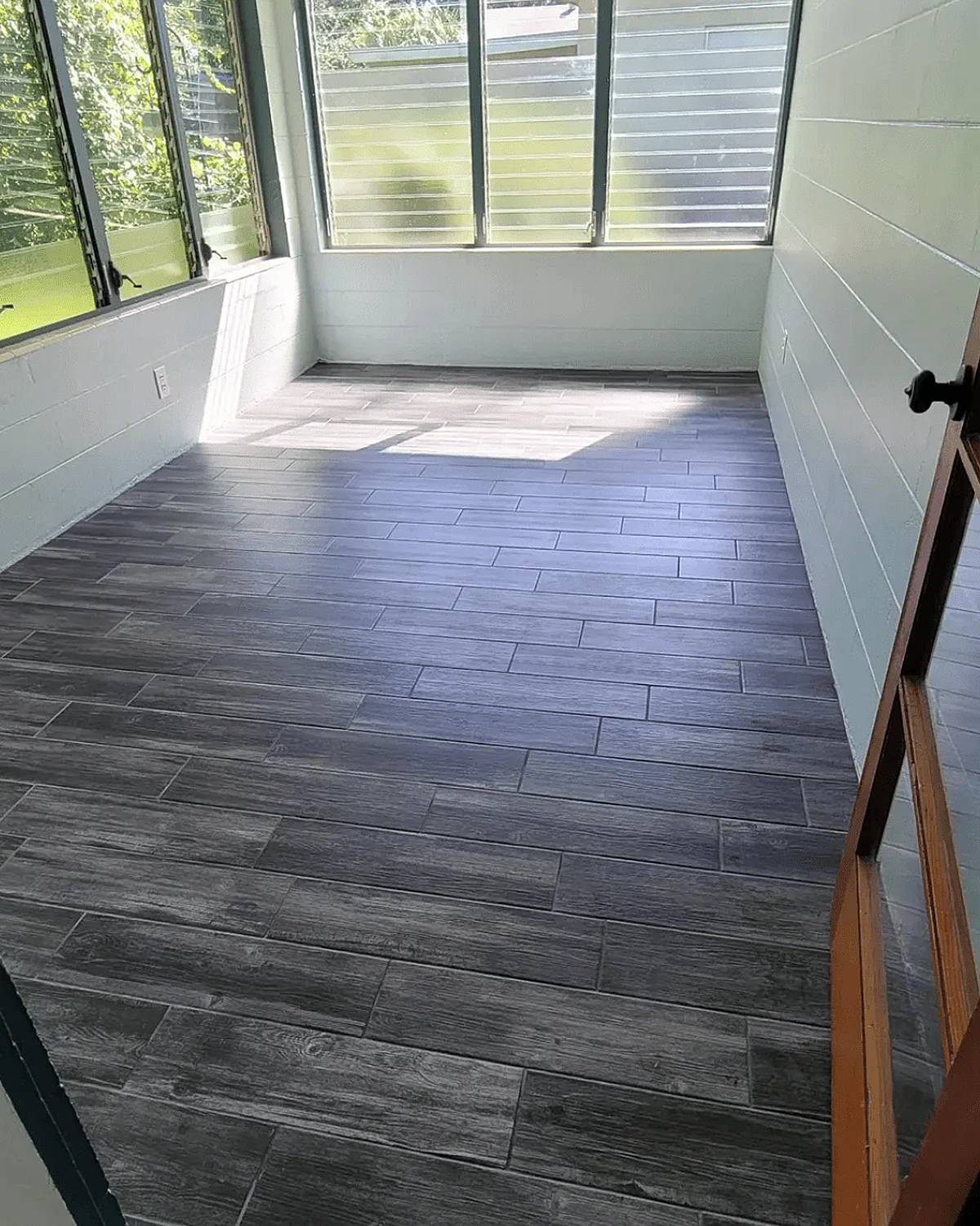 Grey wood-look plank tile floor in a sunroom