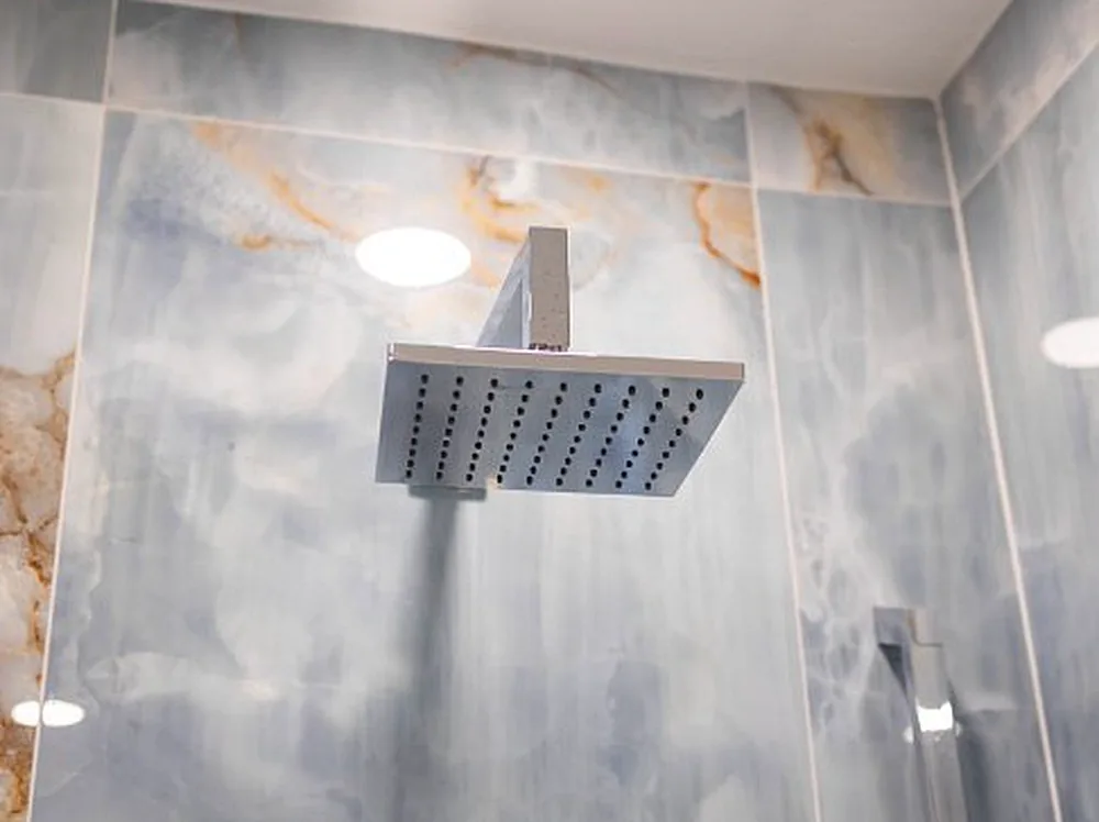 Rain shower head on a blue onyx tile wall